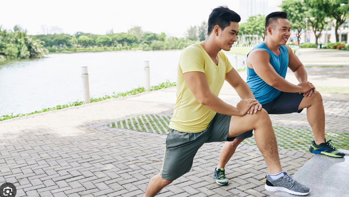 Two friends stretching by a lake before a run