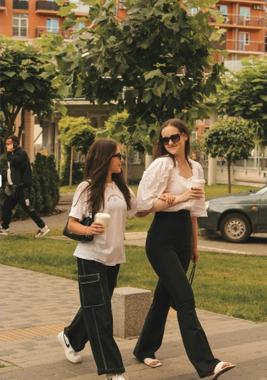 Two friends walking together on a sunny sidewalk